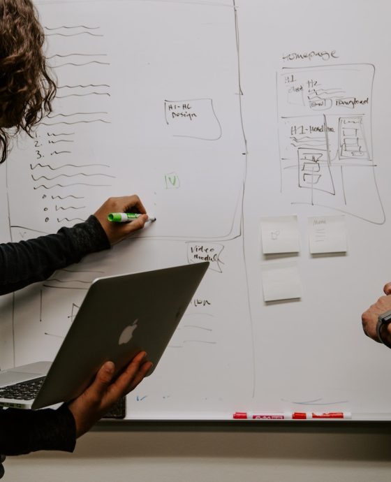 man wearing gray polo shirt beside dry-erase board