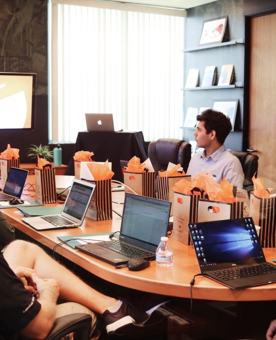 man standing in front of people sitting beside table with laptop computers